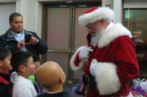 Some children talk to Santa Claus. D.C. Office on Aging Director John Thompson takes pictures.