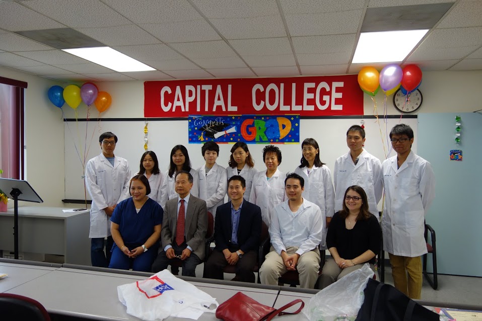 The graduates of Capital College pose for a souvenir photo after the ceremony with the owners and faculty members. Seated at center is Dr. Stephen W. Chang, president of United Medical Laboratories, Inc., manages Capital College, located in Tysons’s Corner in Virginia. 