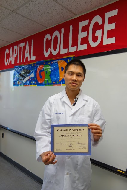Jiamin Liu smiles as he holds his certificate on phlebotomy.